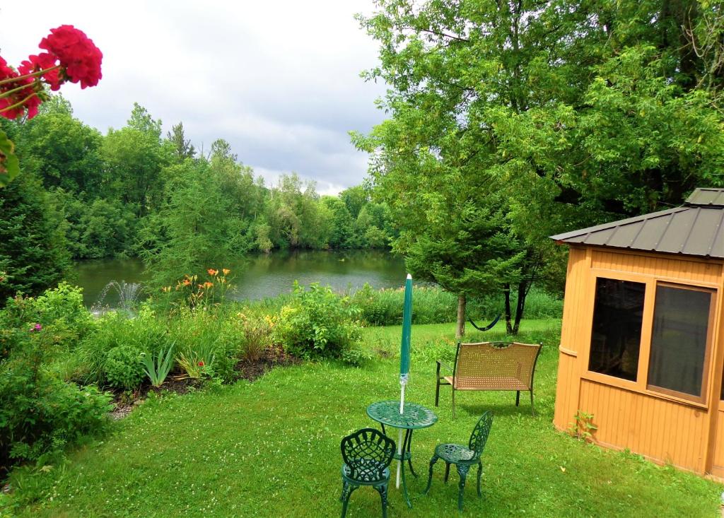 a table and chairs in a yard next to a lake at Motel des Deux Lacs in Waterloo