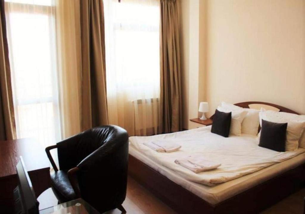 a bedroom with a bed with a chair and a window at Хотел Флора private studio All seasons in Borovets