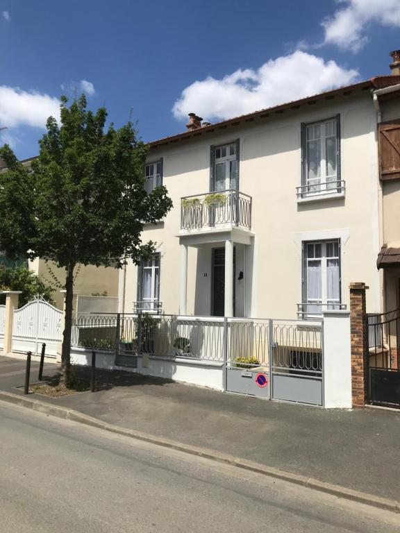 une maison blanche avec une clôture et un arbre dans l'établissement Maison Bernadette - Premier Etage, à Vitry-sur-Seine