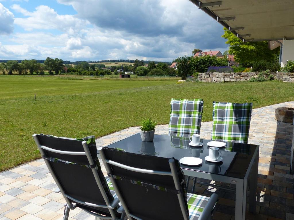 a table and chairs on a patio with a view of a field at Komfort Ferienwohnung Wolfhagen in Wolfhagen