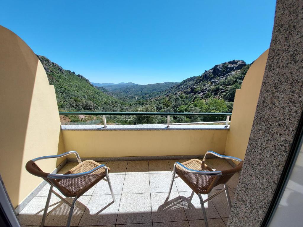 two chairs on a balcony with mountains in the background at Hotel Miracastro in Castro Laboreiro