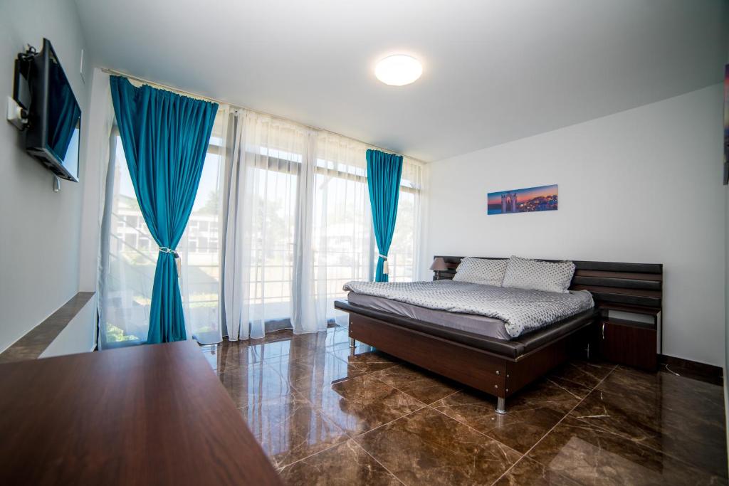 a bedroom with a bed and a large window at Vila Tributte in Neptun