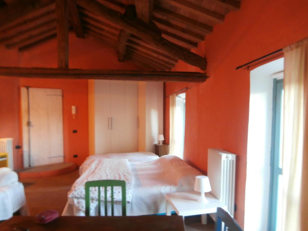 a bedroom with orange walls and a bed and a table at Benvenuti Altrove in Cella Monte