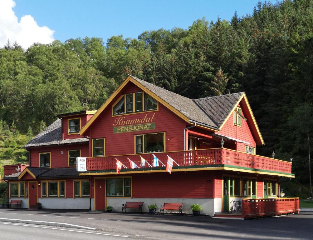 ein rotes Gasthaus mit Flaggen auf der Vorderseite in der Unterkunft Kvamsdal Pensjonat 4 in Eidfjord