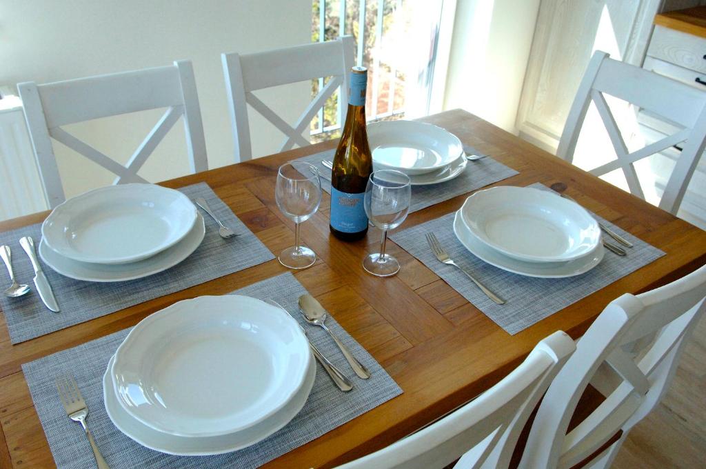 un tavolo in legno con piatti bianchi e una bottiglia di vino di Apartmán Primo Martina a Starý Smokovec