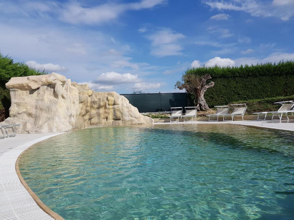 una piscina con sedie e parete di roccia di Relais Casetta 56 a Lugo