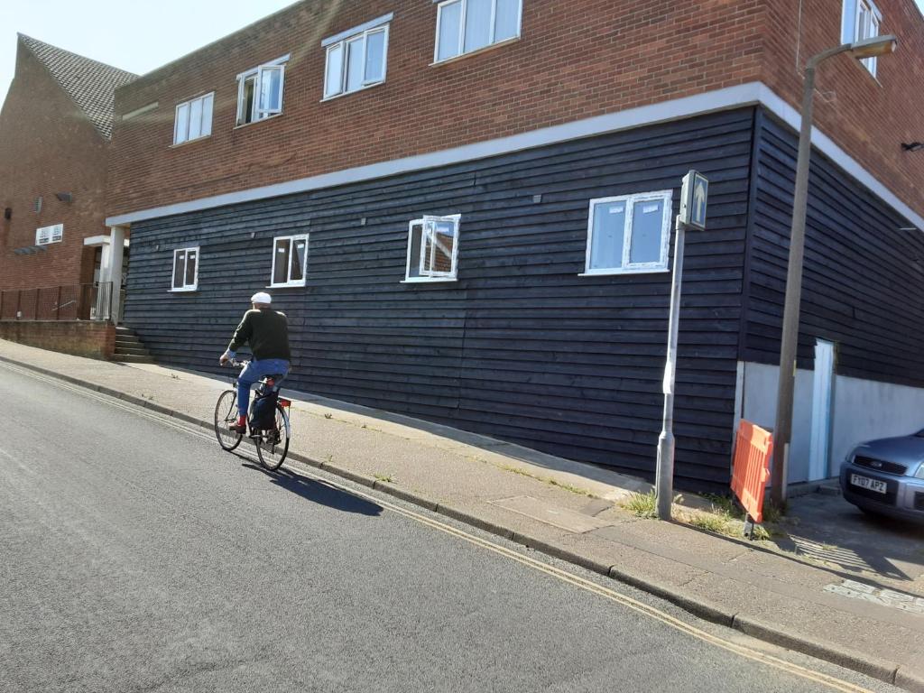 
a man riding a bike down a street next to a building at Rooms at number 4 in North Walsham

