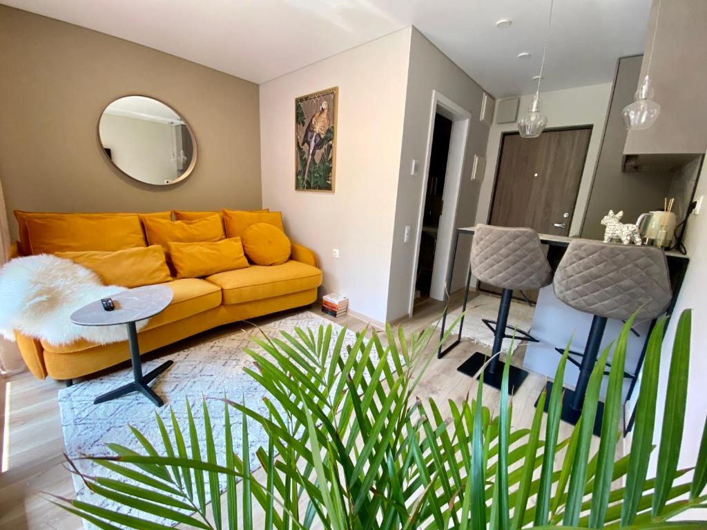 a living room with a yellow couch and a table at Modern Studio Juodkrante in Juodkrantė