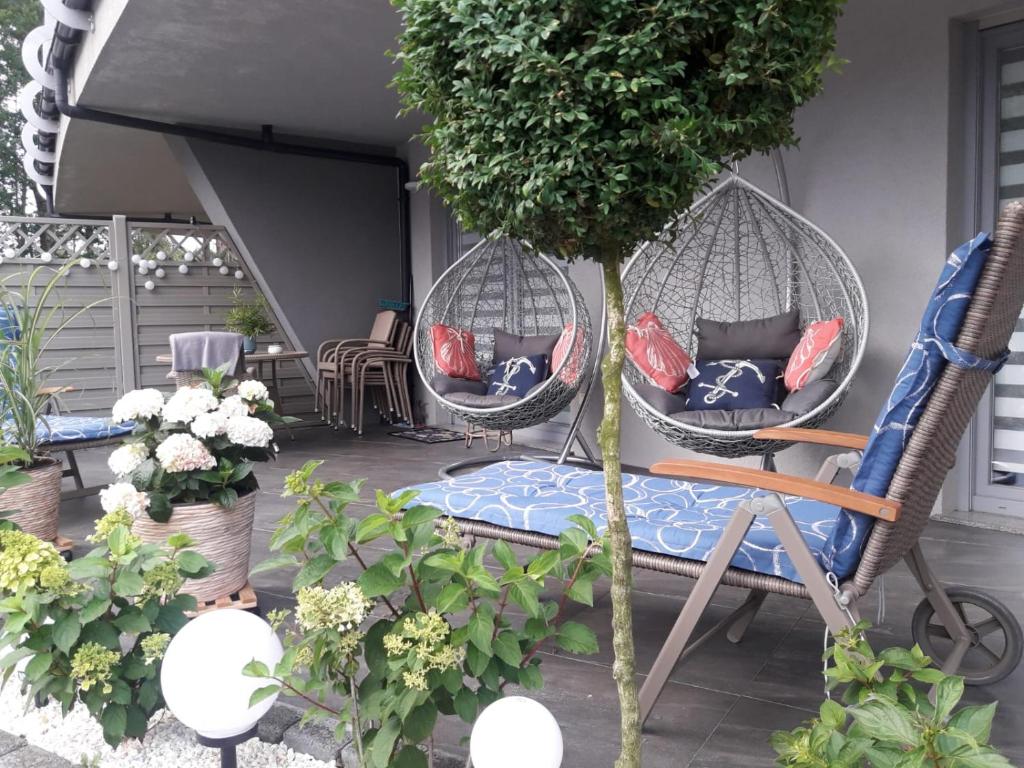 a patio with two wicker chairs and a tree at Apartament Bursztyn in Pobierowo