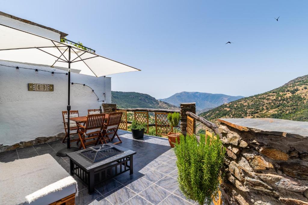 eine Terrasse mit einem Tisch, Stühlen und einem Sonnenschirm in der Unterkunft Casa de Arriba in Capileira