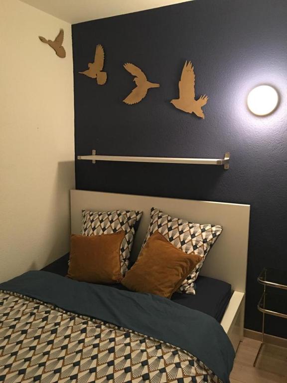 a bedroom with a bed with birds on the wall at Studio Cime de l'Est in Vérossaz