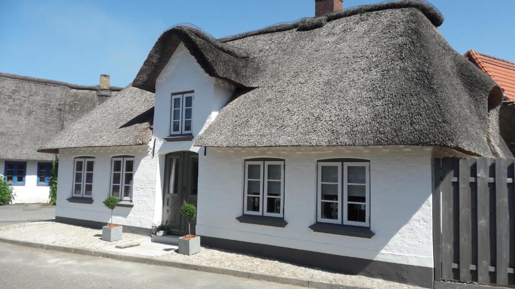 a cottage with a thatched roof on a street at Dat Schmucke Huus in Schwabstedt