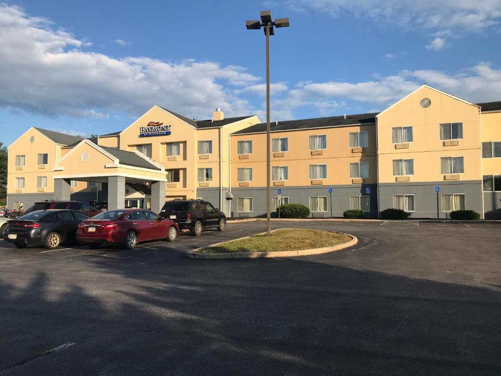 un grand hôtel avec des voitures garées dans un parking dans l'établissement Baymont by Wyndham Chambersburg, à Chambersburg