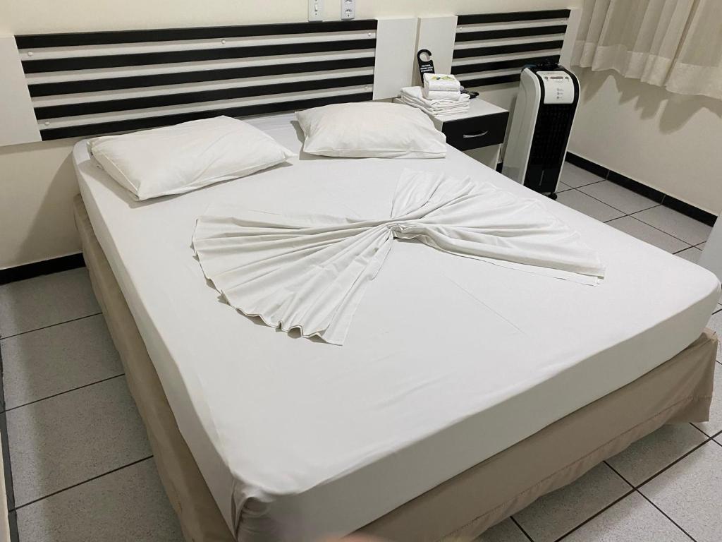 Una cama blanca con un arco encima. en Oft Neve's hotel en Goiânia