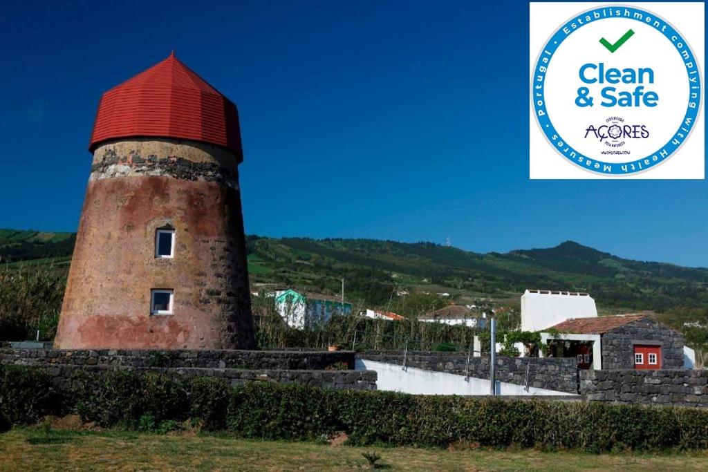 a brick tower with a red roof with a sign for clean and sale at O Moinho Da Bibi in Sete Cidades