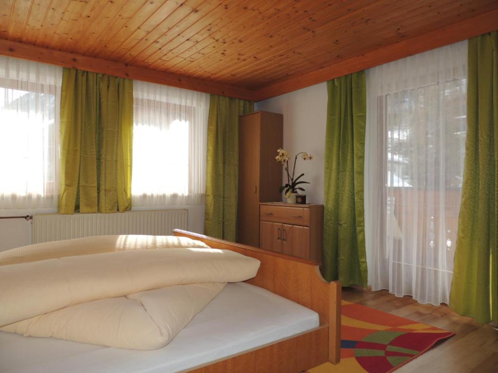 - une chambre avec un lit et des rideaux verts dans l'établissement Haus Praxmarer, à Kaunertal