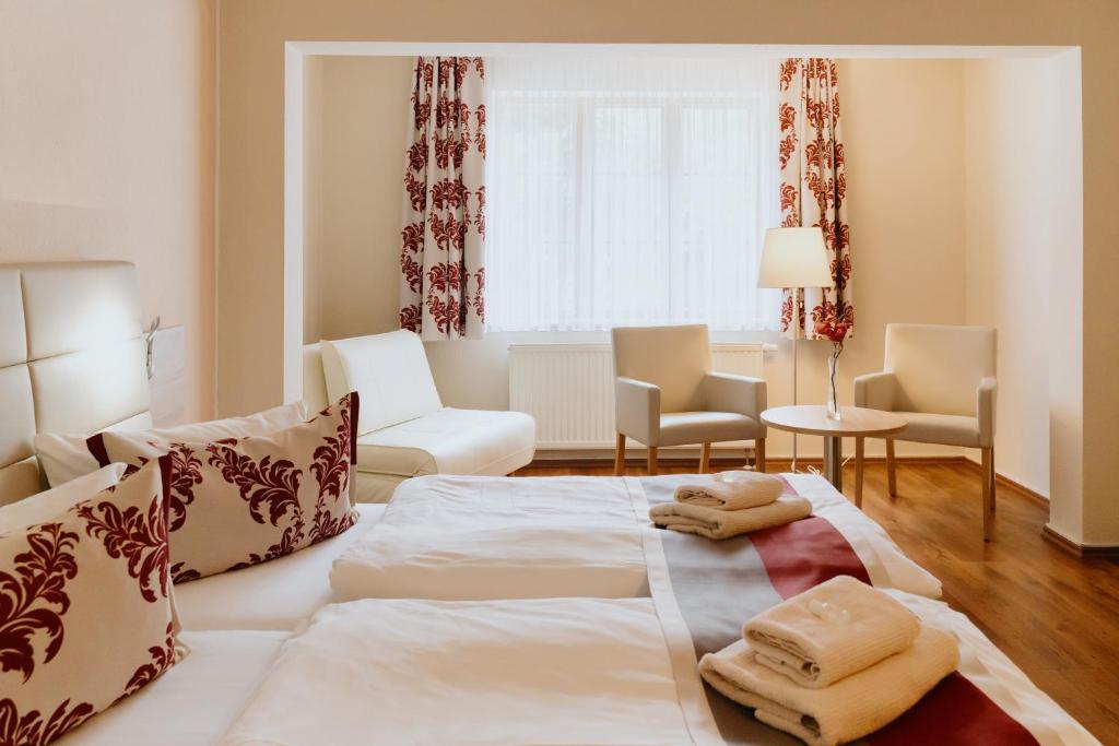 a hotel room with a large bed and chairs at Hotel An den Bleichen in Stralsund