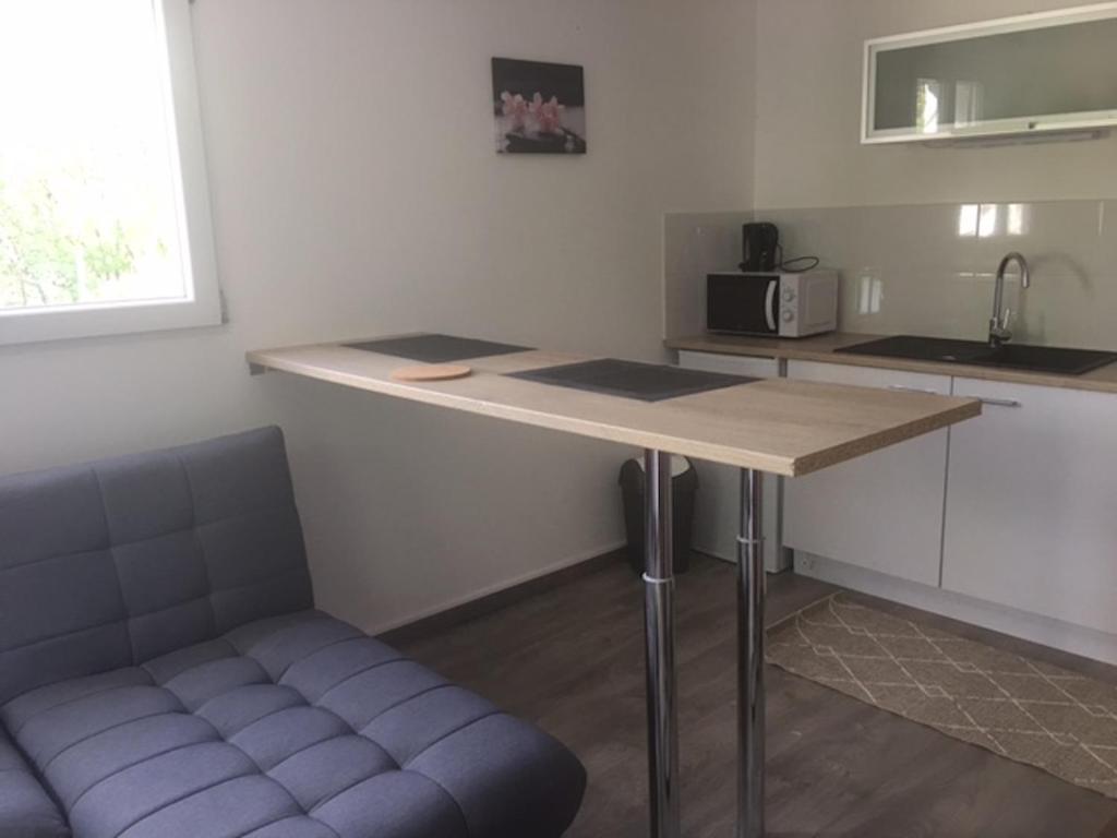 a kitchen with a counter and a table and a couch at Les Glycines in Nicole