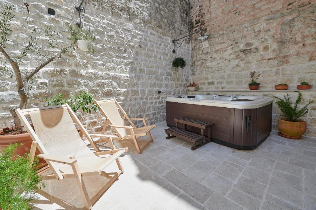 a patio with two chairs and a bath tub at Villa Kudelik - Stone Story in Trogir
