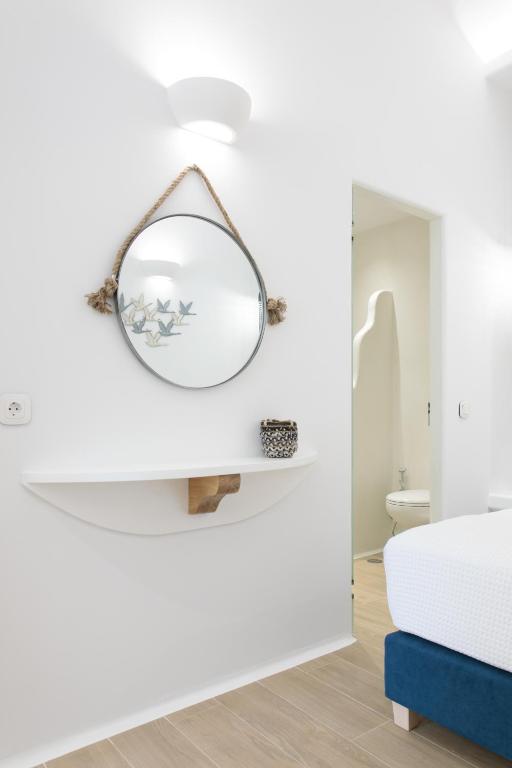 a white bedroom with a mirror on the wall at Hora Seaside Suites in Naxos Chora