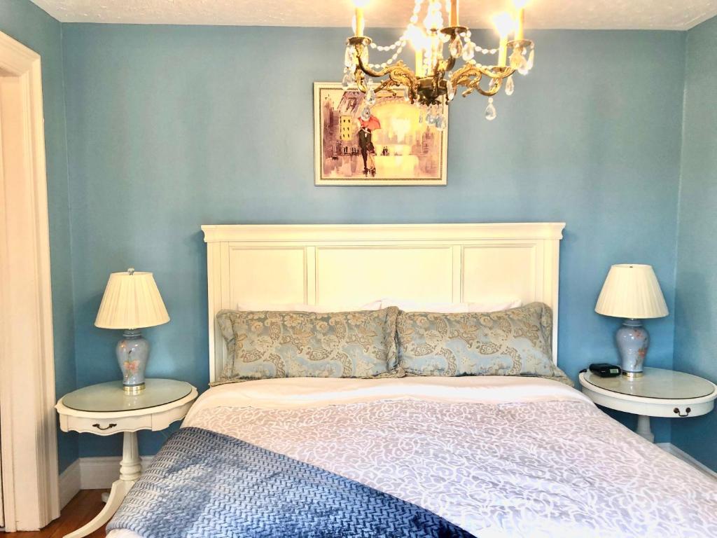 a bedroom with a bed with two tables and a chandelier at Redwood Bed and Breakfast in Niagara Falls