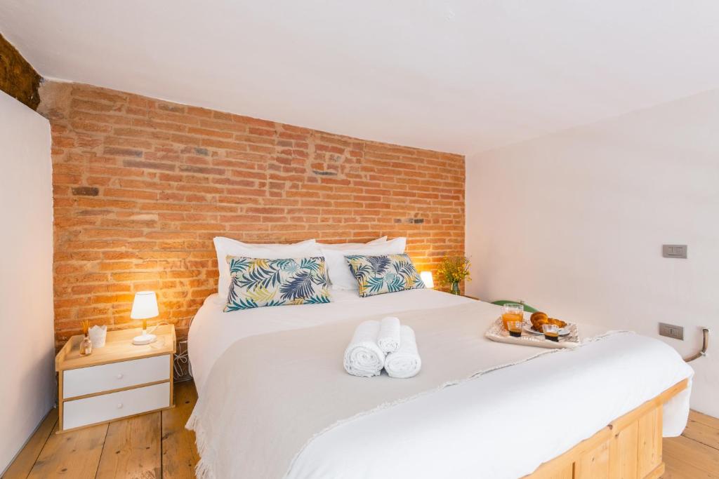 sypialnia z dużym białym łóżkiem z ceglaną ścianą w obiekcie LUI Tuscany Loft w mieście San Miniato