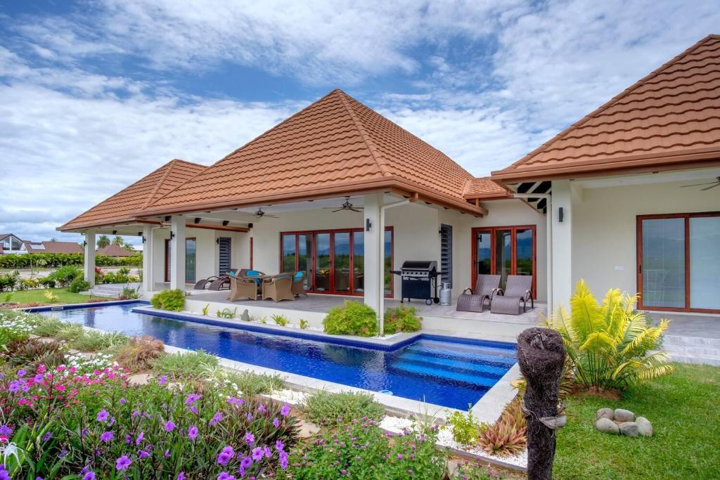 a villa with a swimming pool and a house at Naisoso Island Villas - Fiji in Nadi