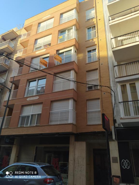 a brown building with balconies and a car parked in front at Pura Vida in Águilas