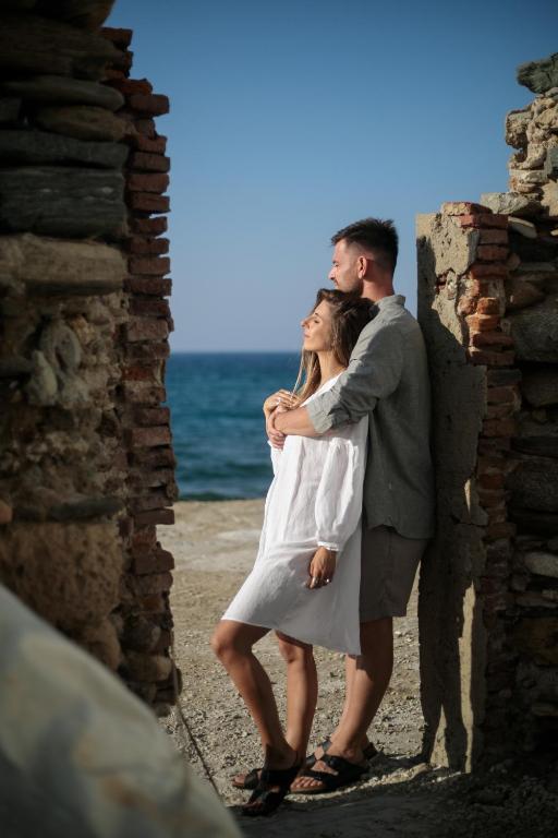 a man and a woman standing next to the ocean at Hora Seaside Suites in Naxos Chora