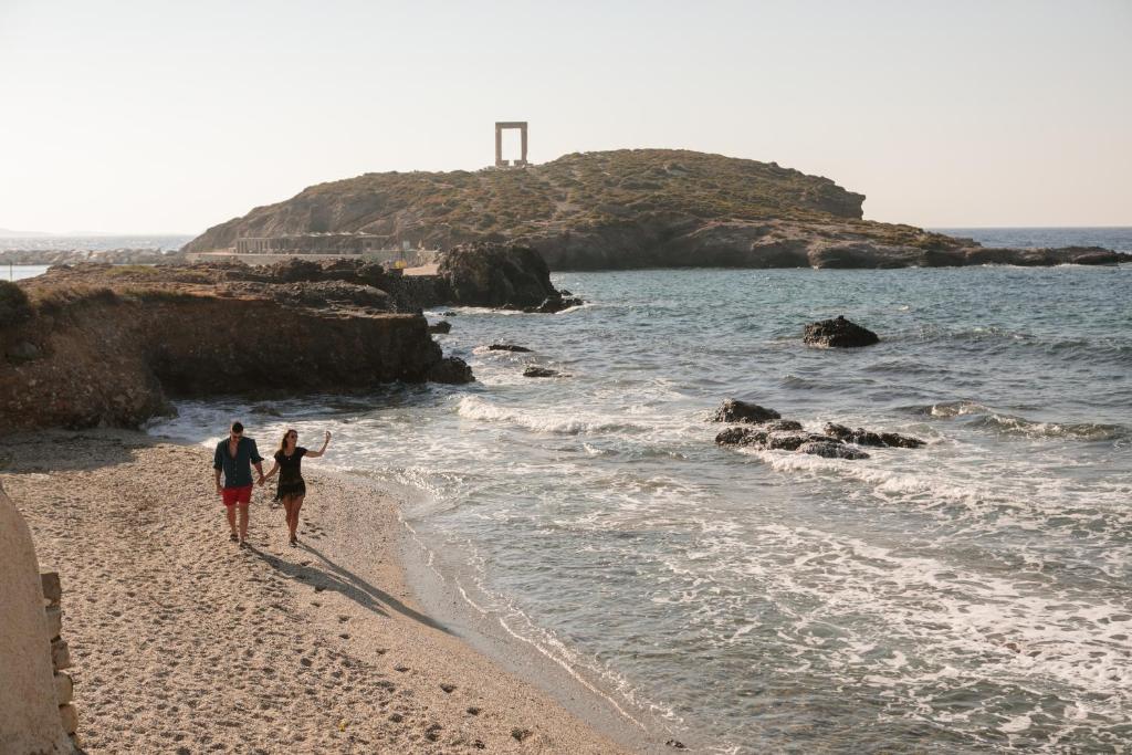 a man and a woman walking on the beach at Hora Seaside Suites in Naxos Chora