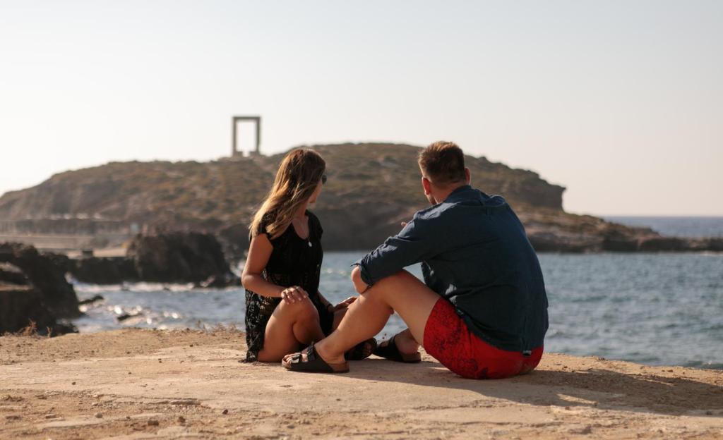 a man and a woman sitting on the beach at Hora Seaside Suites in Naxos Chora