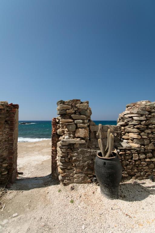 a vase sitting on the beach next to a stone wall at Hora Seaside Suites in Naxos Chora
