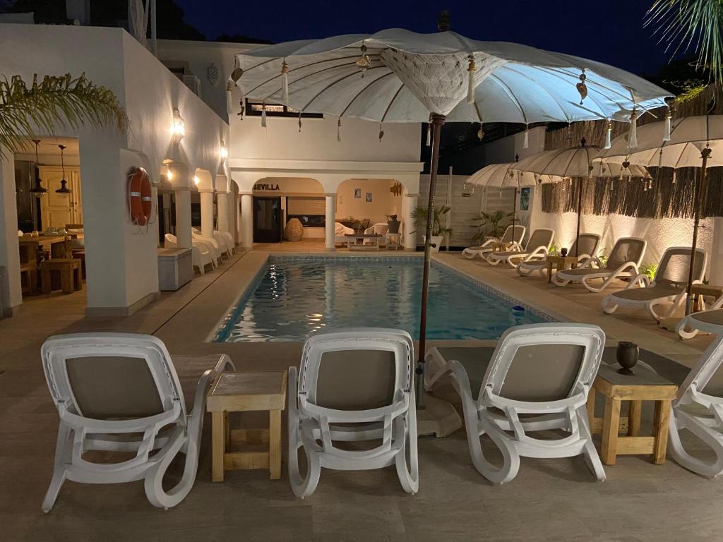 een zwembad met stoelen en een parasol bij Casa Holandaluzas Marbella near Beach, with salt water Pool and private parking in Marbella