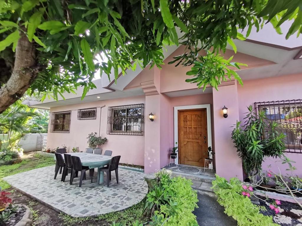 une maison rose avec une table et des chaises devant elle dans l'établissement Magayon Pink House, à Legazpi