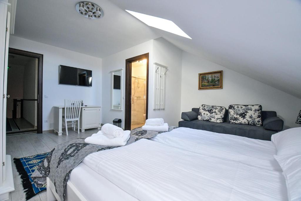 a bedroom with a large white bed and a couch at Casa Alexandru – Locul în care te simți acasă in Vişeu de Jos