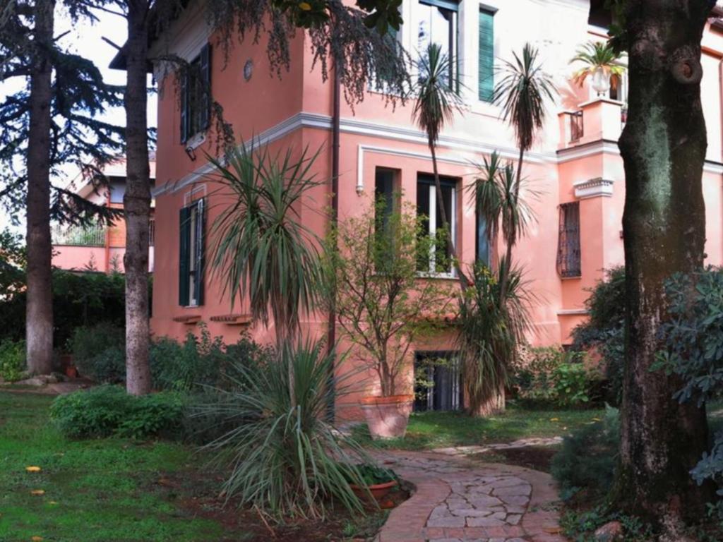 a pink building with palm trees in front of it at Villino Corbelli B&B in Rome