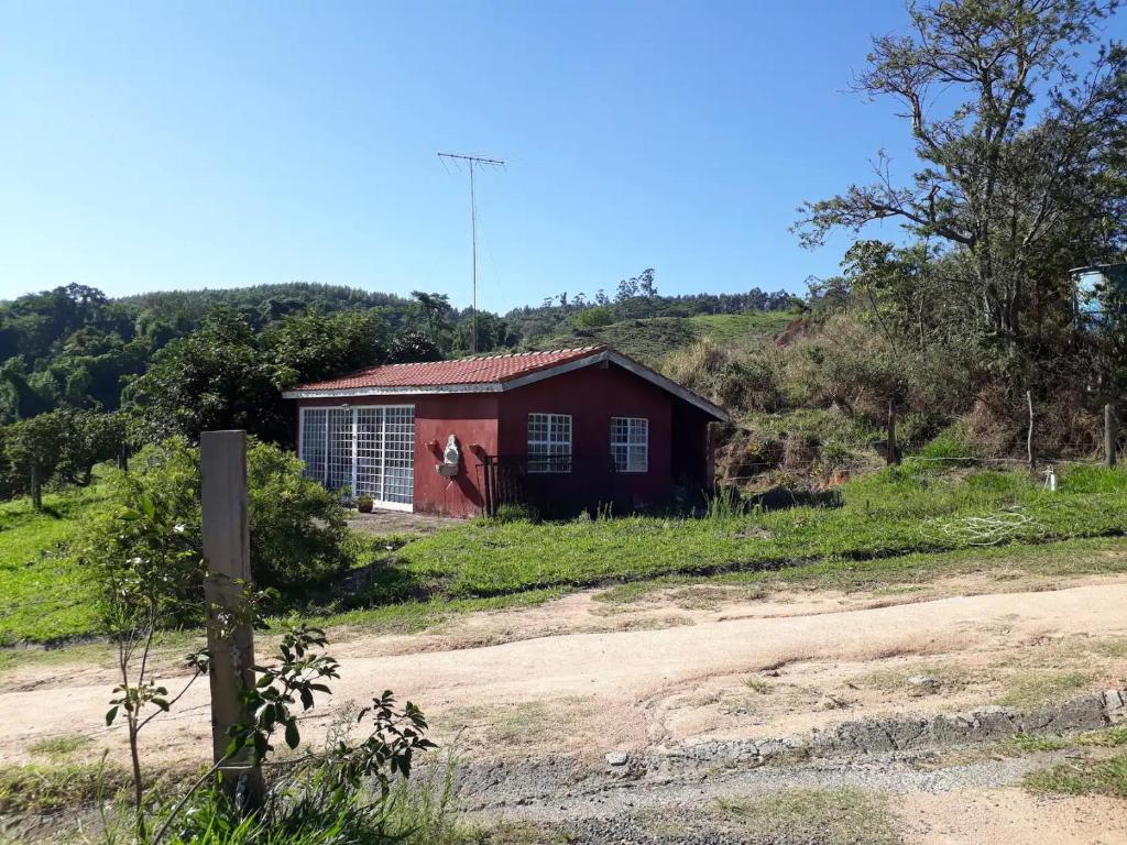 a red house on a hill next to a dirt road at Casa de Campo-Linda Vista-SOUSAS in Campinas