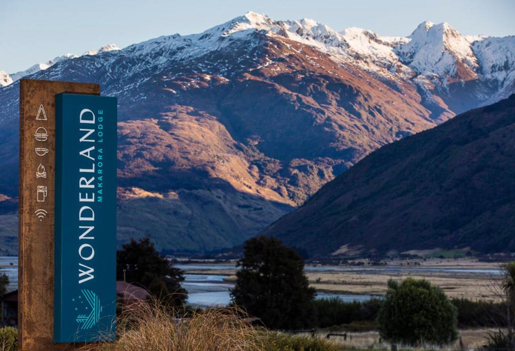 a sign in front of a snow covered mountain at Wonderland Makarora Lodge in Makarora