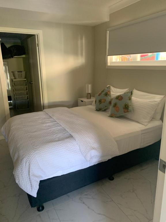 um quarto com uma cama grande com lençóis brancos e almofadas em Victoria 53 em Brisbane
