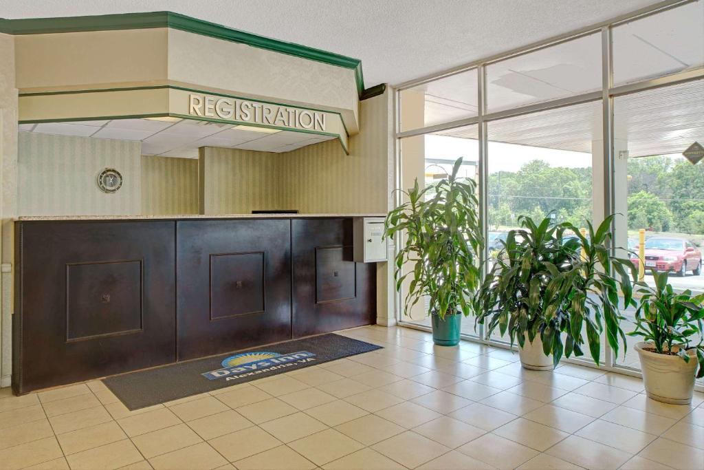 a hotel lobby with a reception desk and potted plants at Days Inn by Wyndham Alexandria South in Alexandria
