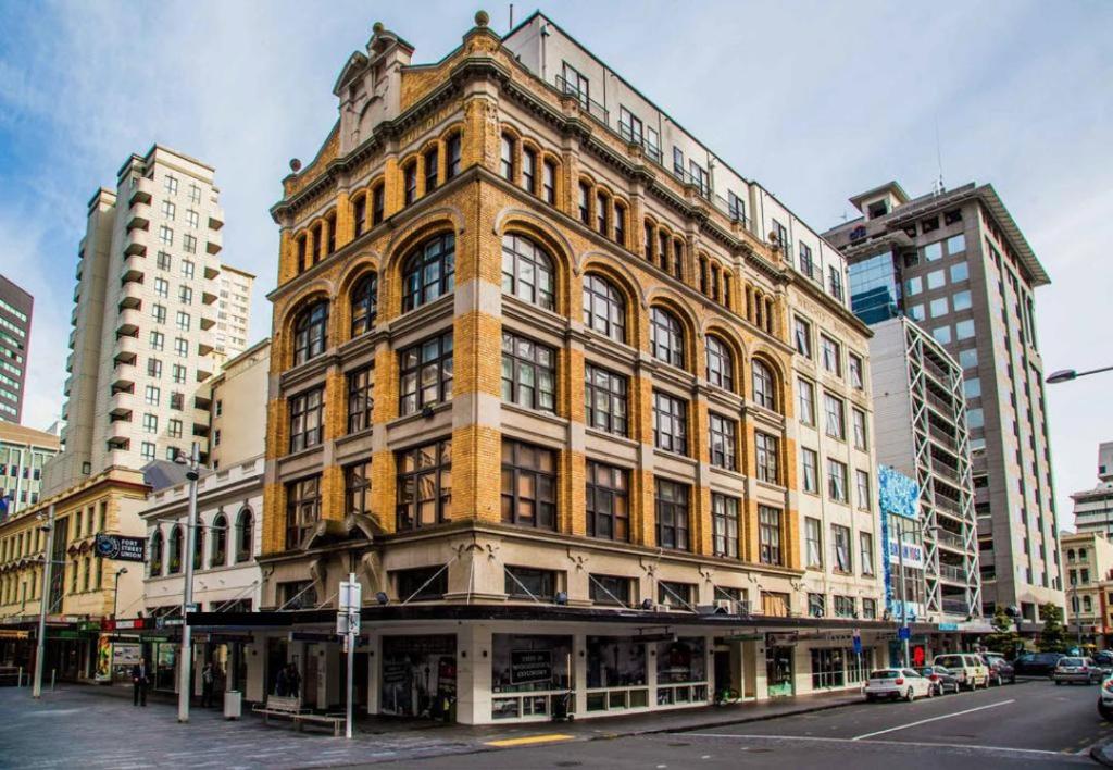 un grand bâtiment au coin d'une rue de la ville dans l'établissement Fort Street Accommodation, à Auckland