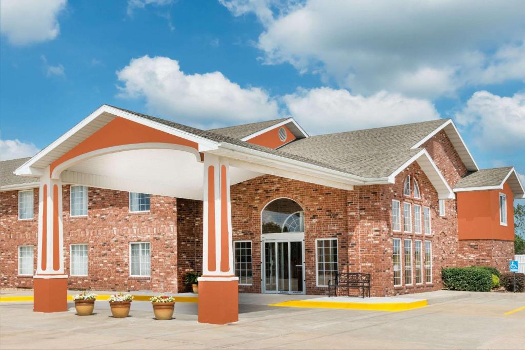 a large brick building with a large porch at Super 8 by Wyndham Bolivar in Bolivar