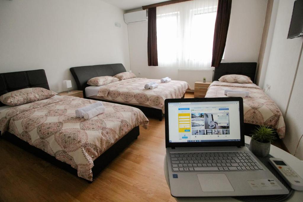 a room with two beds and a laptop on a desk at Apartments Station in Konjic