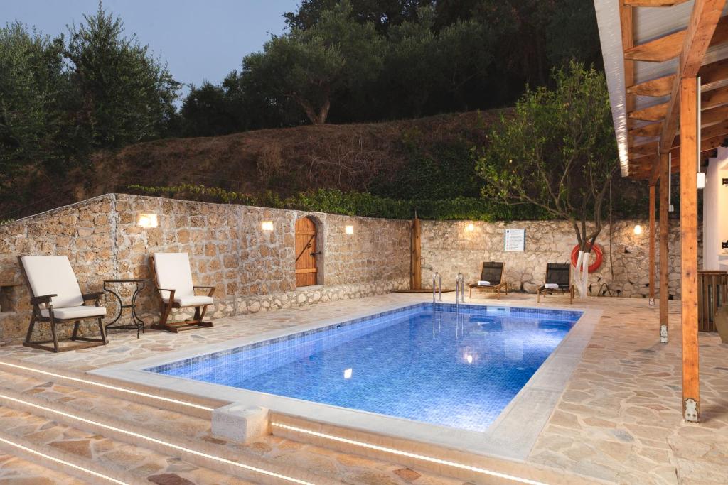 una piscina en un patio con sillas y una pared de piedra en Villa Rocale en Argasi