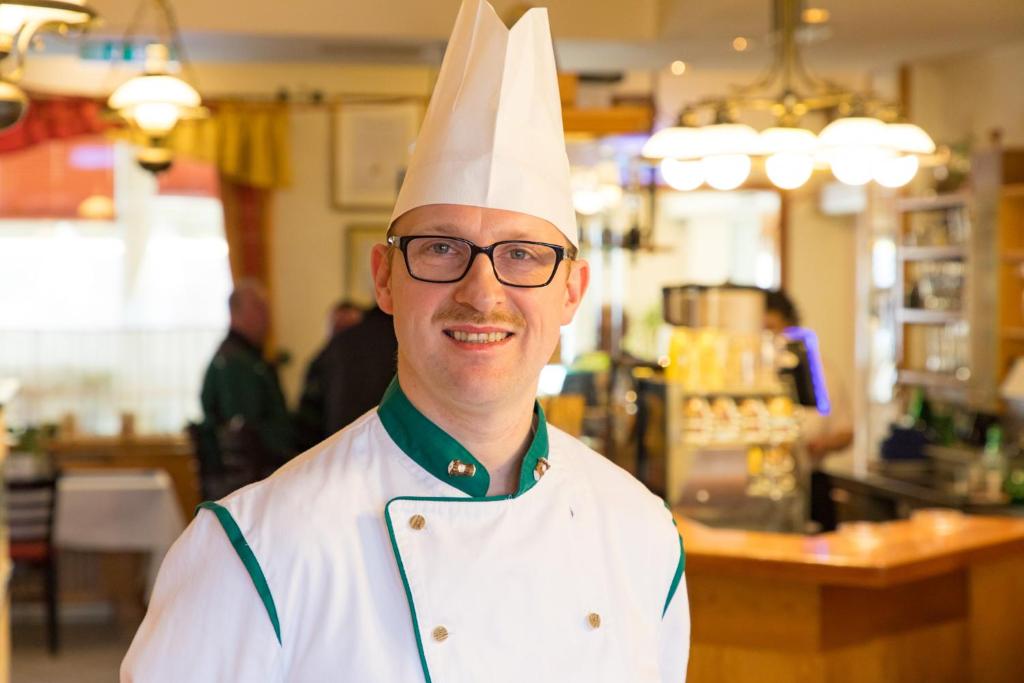 a man wearing a chefs hat and glasses at Hotel Freiensteinerhof Superior in Sankt Peter-Freienstein