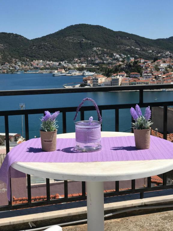 a purple table with a bucket and flowers on a balcony at Beautiful view of poros in Galatas