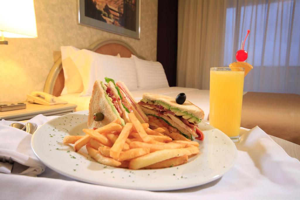 a sandwich and french fries on a plate with a drink at Holiday Inn Monterrey-Parque Fundidora by IHG in Monterrey