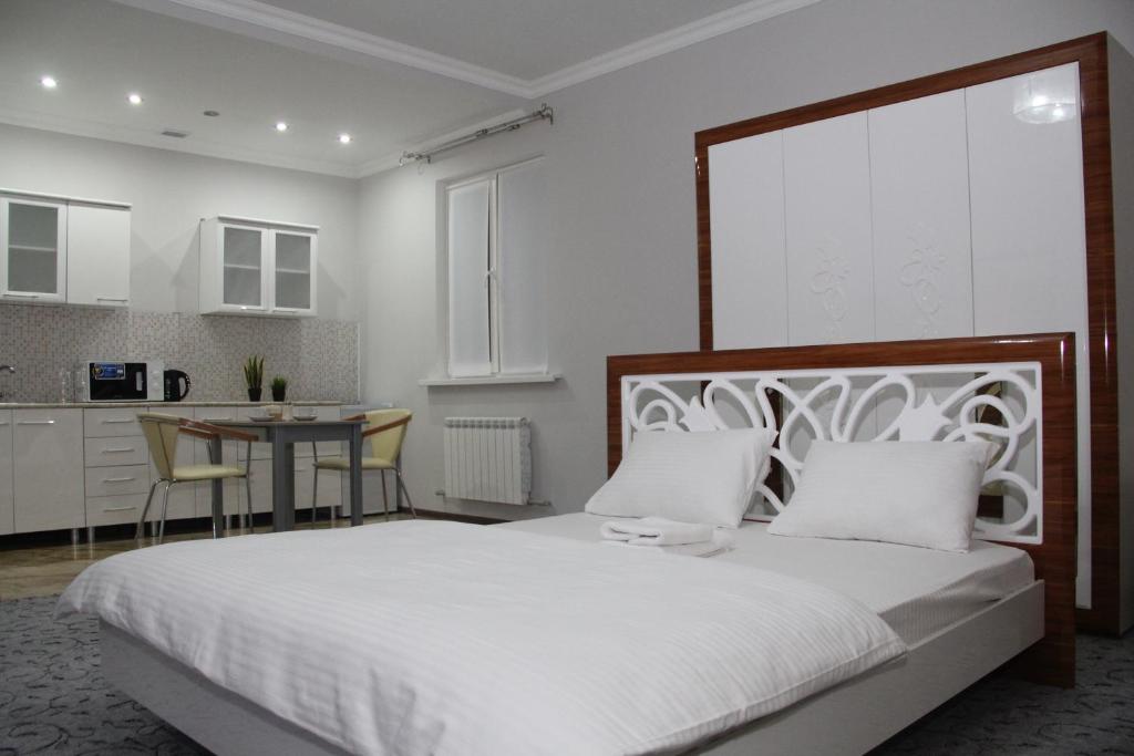 a bedroom with a large white bed and a kitchen at Sarai-Batu Guest House in Atyrau