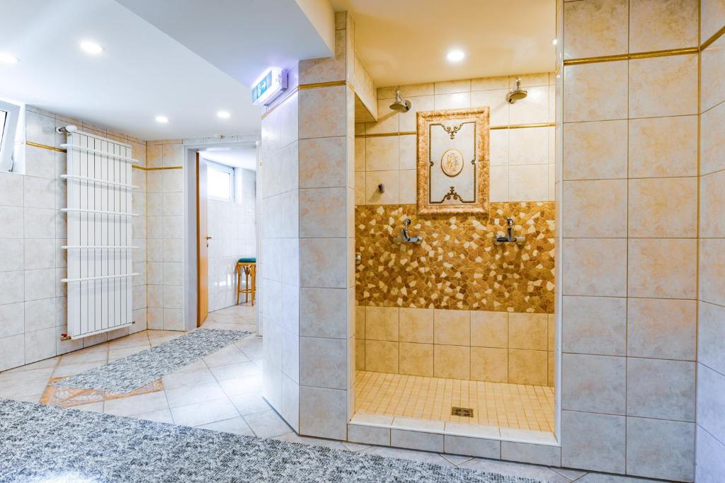 a large bathroom with a shower with a clock on the wall at Hotel Freiensteinerhof Superior in Sankt Peter-Freienstein