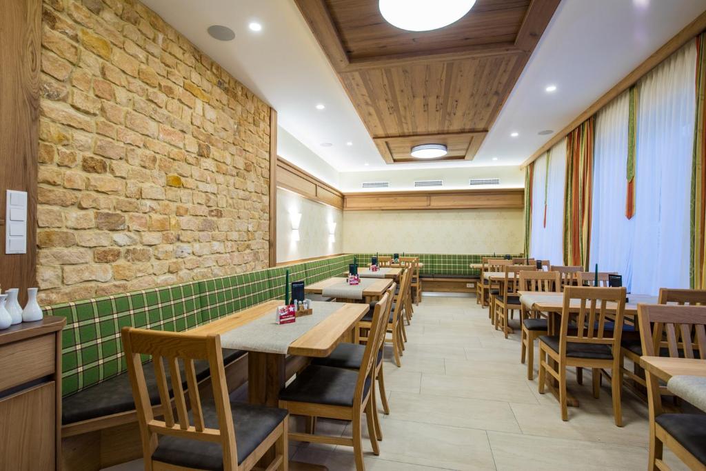 a restaurant with wooden tables and chairs and a brick wall at Hotel Freiensteinerhof Superior in Sankt Peter-Freienstein